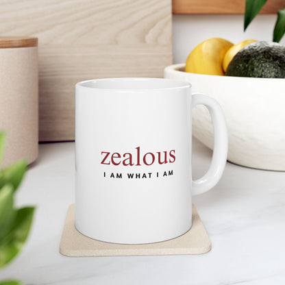 White mug with 'zealous I AM WHAT I AM' text on a coaster, surrounded by plants and a bowl of fruit.