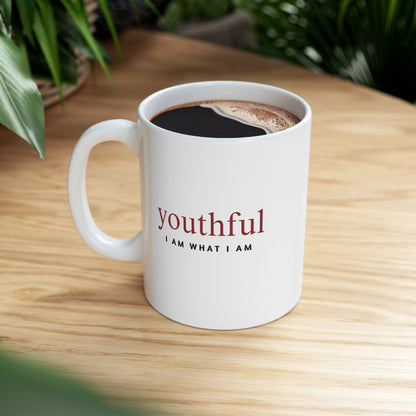 White mug with 'youthful I AM WHAT I AM' text on a wooden table with coffee.